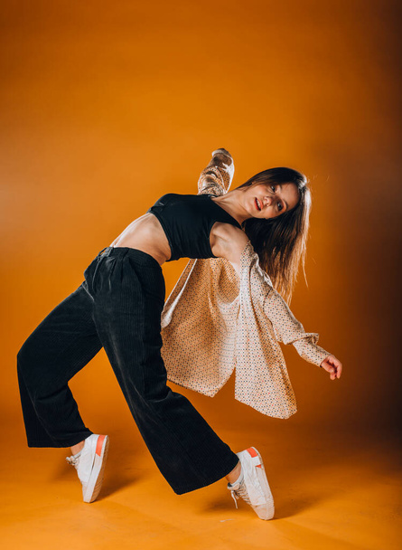 Впишеться молода дівчина танцюрист, виконуючи танцювальну рутину в помаранчевій студії
 - Фото, зображення