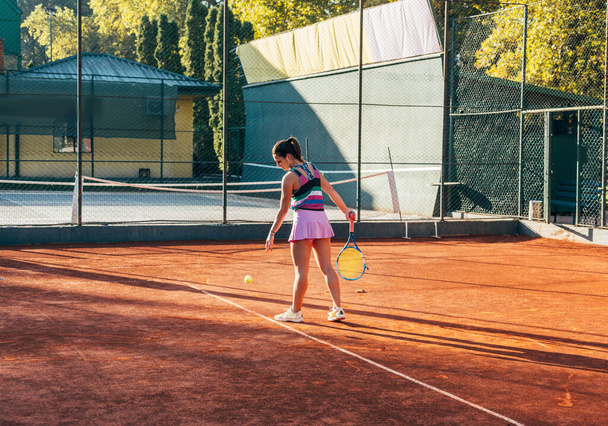 Una giovane tennista che serve su un campo di argilla - Foto, immagini