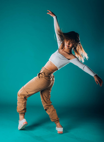 Flexibel atletisch meisje tijdens een intense dansoefening in een moderne cyaan studio - Foto, afbeelding