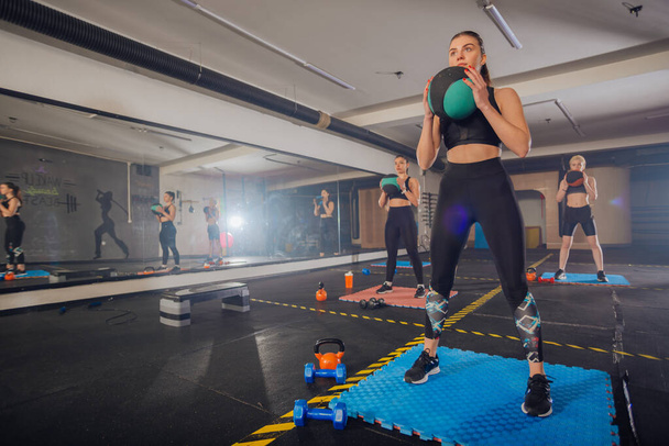 Gruppo fitness di quattro donne attraenti che fanno esercizi e squat con una palla medica - Foto, immagini