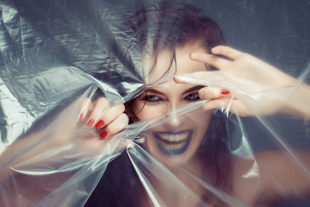 Woman with creative eye makeup peering cellophane - Fotó, kép