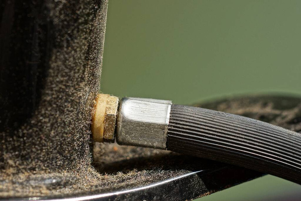 parte de una manguera de goma con una tuerca de metal gris en una bomba de metal sucio negro - Foto, Imagen
