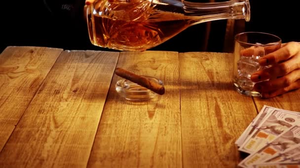 Close-up zicht op de man handen die zit aan houten tafel en giet whisky in een glas in slowmo - Video
