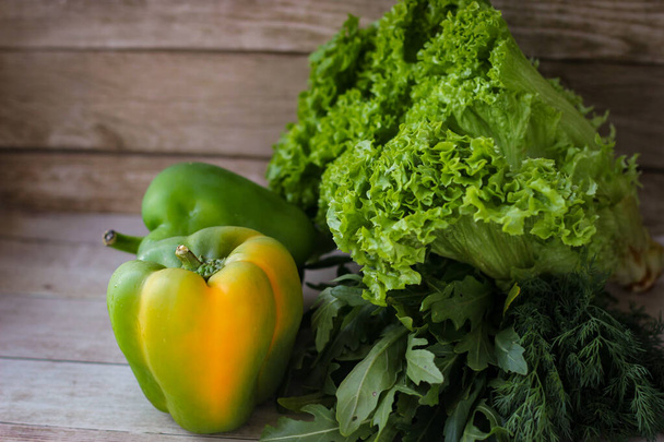 El concepto de alimentación saludable. Hojas de eneldo verde y rúcula, y lechuga junto con pimiento verde sobre un fondo de madera - Foto, Imagen