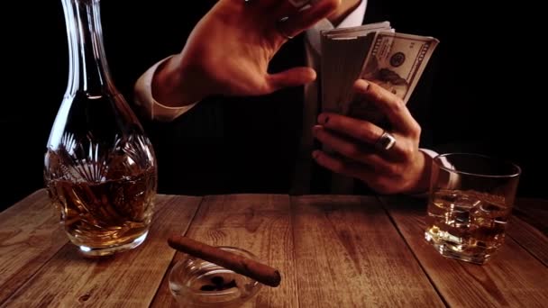 Заможний чоловік в елегантному чорному костюмі відпочиває в барі і бризкає гроші в повільному русі
 - Кадри, відео