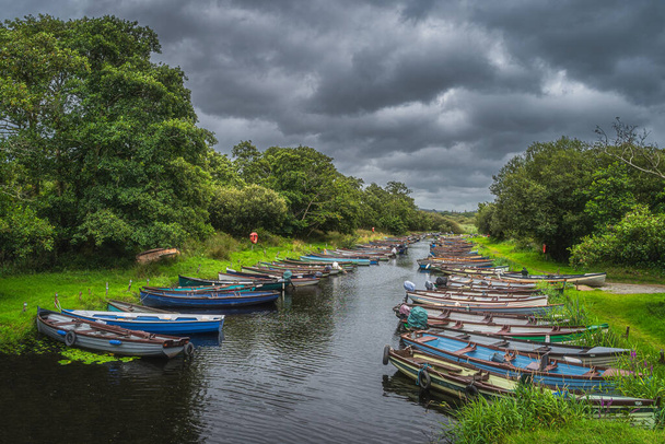 Lough Leane, Ring of Kerry, Killarney, İrlanda yakınlarındaki yemyeşil ağaçlarla çevrili nehir veya kanalda demirli tahta kürek tekneleri veya motorlu tekneler. - Fotoğraf, Görsel