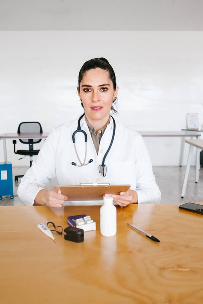 Portrait Of latin Female Doctor Wearing White Coat With Stethoscope In Hospital Office in Mexico city - Photo, Image