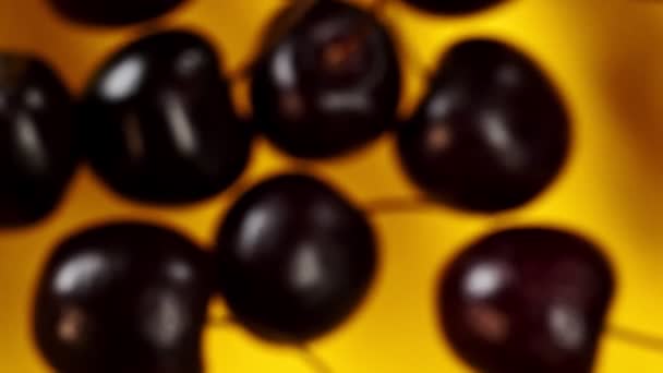 Cherries fly on a yellow background in slow motion - Footage, Video