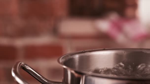 Water boiling in steel pot. Bubbles of boiling water. Male hand close saucepan cover. Slow motion shot. - Footage, Video