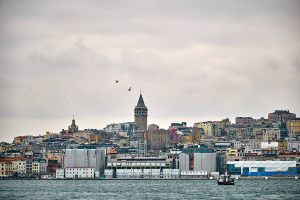 Turkey istanbul 04.03.2021. Famous galata tower of istanbul taken photo from istanbul bosporus. it is established by genoese sailors for watching of bosporus of constantinople with seagulls on sky - Photo, Image