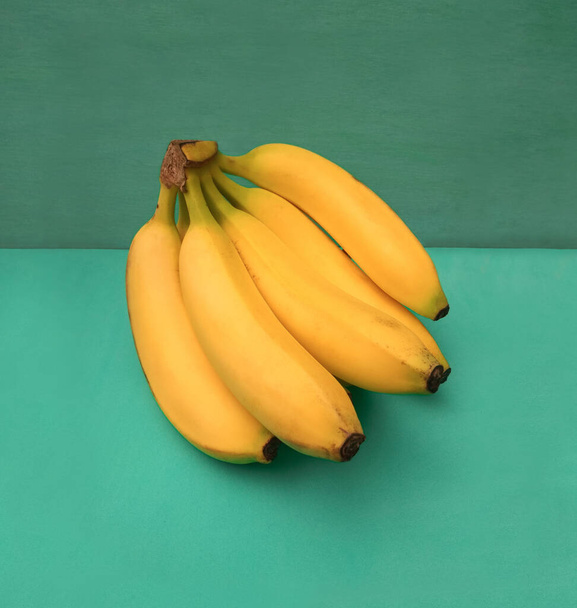  fresh yellow bananas on turquoise background - 写真・画像