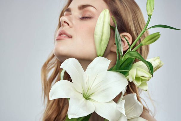 Retrato de una hermosa mujer con flores blancas sobre un fondo claro - Foto, imagen