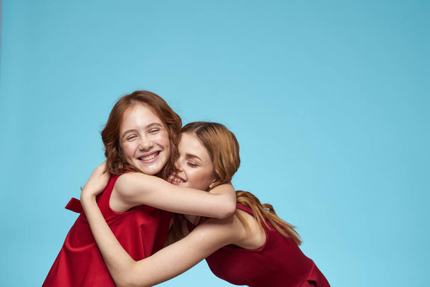 Anya és lánya piros ruhák szórakoztató életmód szórakoztató stúdió kék háttér - Fotó, kép