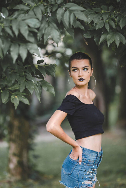 A shallow focus shot of a confident Caucasian female posing for the camera in a park - Foto, Imagem