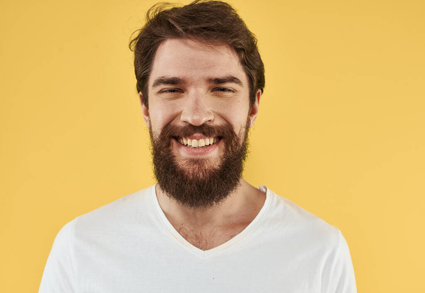 Portrait of a guy in a t-shirt and a brunet beard model yellow background - Valokuva, kuva