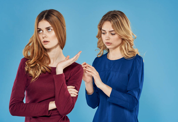 две девушки в платье конфликт эмоций синий фон студии - Фото, изображение