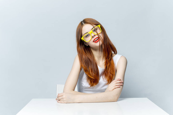 mulher em óculos amarelos sentado à mesa sorriso  - Foto, Imagem