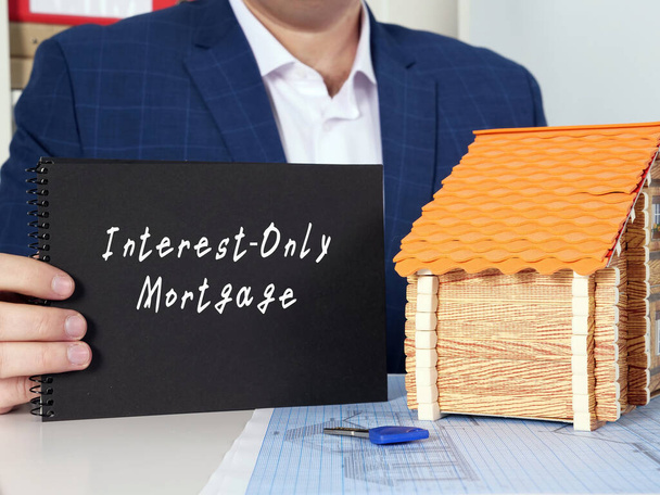 Concepto financiero sobre hipoteca solo de interés con cartel en bloc de notas negro en la mano. - Foto, imagen