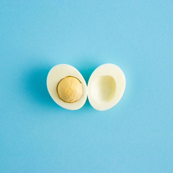 Creativo concetto di arte pasquale con fette di uovo naturale e tuorlo d'uovo su sfondo azzurro. Minimale concetto di vacanza primaverile - Foto, immagini