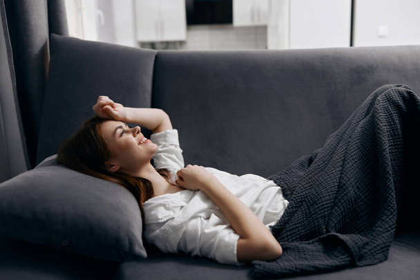 емоційна жінка лежить на дивані і м'якій подушці внутрішній обрізаний вид
 - Фото, зображення
