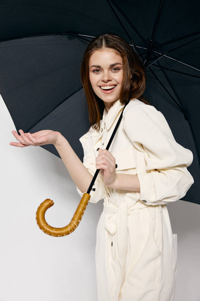fröhliche hübsche Frau mit Regenschirm in den Händen Schutz vor Regen Licht Anzug Studio - Foto, Bild