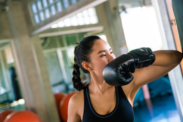 Μπόξερ γυναίκες punching τσάντα σε ένα στούντιο πυγμαχίας. Ασιάτισσες αμυντικές ασκήσεις - Φωτογραφία, εικόνα