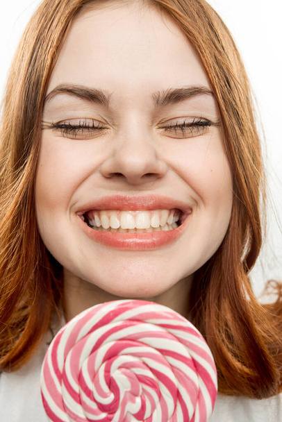 Frau mit offenem Mund hält Lutscher in Gesichtsnähe Süßigkeiten Freude  - Foto, Bild