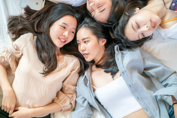 Top view self portrait of attractive pretty girls friends group lying on white bed talking scret looking at camera - Photo, Image