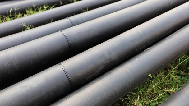 Welded joints on HDPE pipes. Polyethylene pipe piles with welded pipe connections raised on the ground side of the roadway with a copy area. Selective focus - Photo, Image