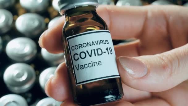 Vrouw hand met potentieel anti-coronavirus vaccin in steriele injectieflacon of fles met geneesmiddelen voor de apotheek - Video