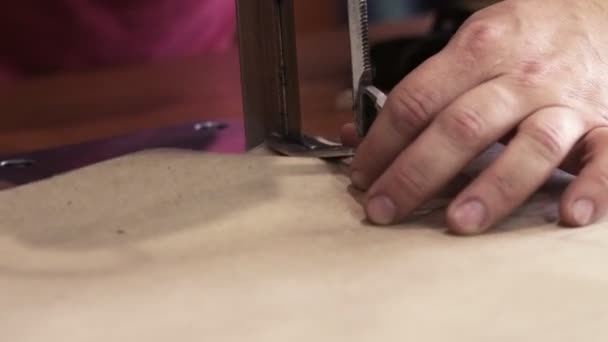 Close-up shot van mannelijke werknemer op een naaimachine maakt gebruik van elektrische snijden stof machine. Naaiproductielijn. Stof snijden - Video