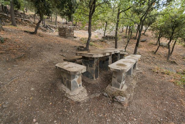 Picnic area in Sierra Nevada, the construction is made of stone, there are trees and bushes - Photo, Image