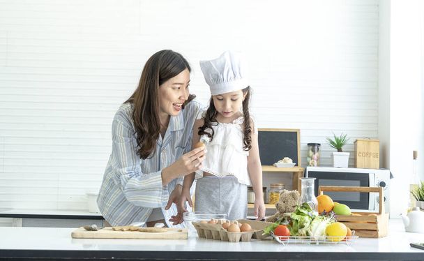 Μητέρα και κόρη, χαριτωμένα παιδιά, φορώντας καπέλα σεφ, διδασκαλία κτιρίου στην κουζίνα - Φωτογραφία, εικόνα