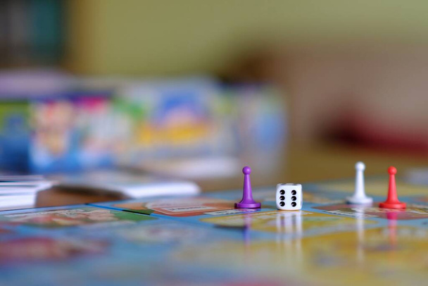 Close-up van een bordspel met gekleurde tokens en een dobbelsteen - Foto, afbeelding