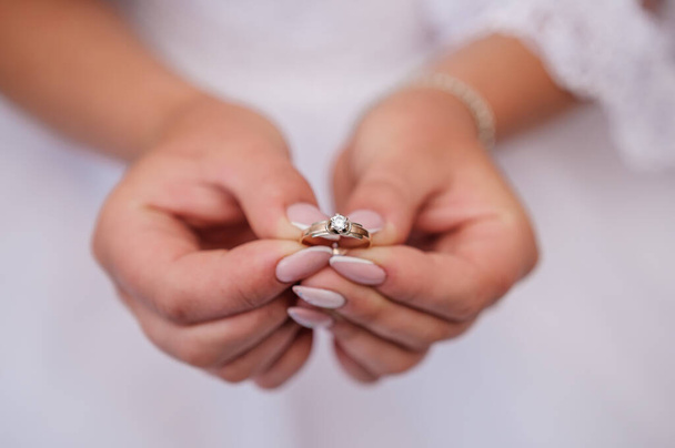 Gouden ring met een steen in de handen van de bruid - Foto, afbeelding