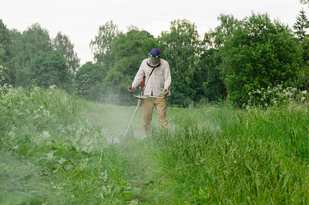 pracovník člověka řez trim mow mokrou trávu po dešti  - Fotografie, Obrázek