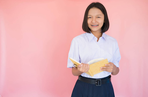 Öğrenci üniforması içinde pembe geçmişi olan Asyalı genç bir kız portresi.. - Fotoğraf, Görsel