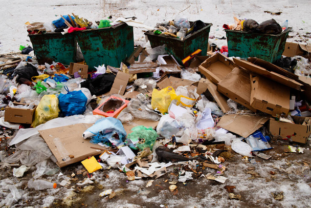 Een stapel afval op een stortplaats, containers en een overvloed aan afval, afval en vervuiling van plastic flessen en zakken op de grond, recycling van afval, het gevaar van giftige milieuvergiftiging. - Foto, afbeelding