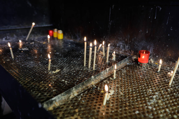 Детали со свечами, зажженными внутри православной церкви для живых и мертвых. - Фото, изображение