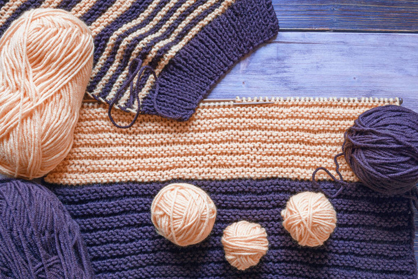 Onvoltooid breien, bollen wol en breinaalden op een rustieke tafel. Ruimte voor tekst - Foto, afbeelding
