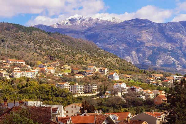 Όμορφο ορεινό τοπίο την ηλιόλουστη ανοιξιάτικη μέρα. Πράσινη πόλη στους πρόποδες των βουνών. Μαυροβούνιο, άποψη των χιονισμένων κορυφών του βουνού Lovcen και της πόλης Tivat - Φωτογραφία, εικόνα