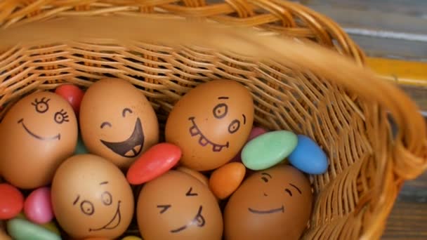 カラフルなキャンディー、イースターの準備、休日の気分の概念を持つわらバスケットに手描きの笑顔の卵のスタック - 映像、動画