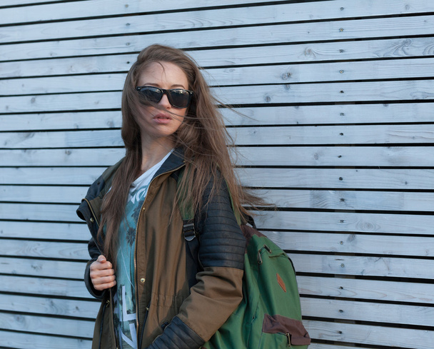 Beautiful Girl Long Hair. Tourist jacket, Backpack. white wooden wall. - Foto, Imagem