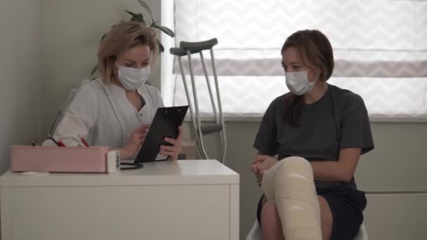 Egy gyönyörű női orvos felveszi mankó a beteg műtét után a lábát - Felvétel, videó