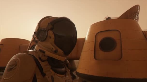 Astronauta en el planeta Marte, haciendo un desvío alrededor de su base. Astronauta caminando por la base. Pequeña tormenta de polvo. La antena parabólica envía datos al suelo. Animación 3D realista - Metraje, vídeo