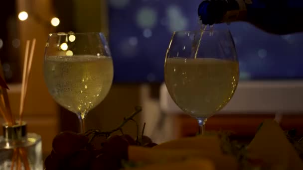 Bubbels in wijnglas gevuld met witte mousserende wijn op de buffettafel. Witte wijn geserveerd of gegoten in een transparant glas met nieuwjaars- en kerstviering thema concept. - Video