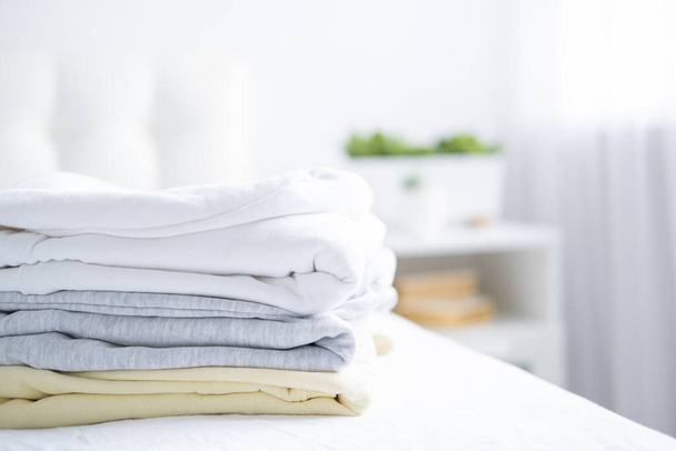 stapel vrouwen kleurrijke sweatshirts, hoodies in pastelkleuren op wit bed. Seizoensgebonden winkelen, wasserij, vakantie concept. - Foto, afbeelding