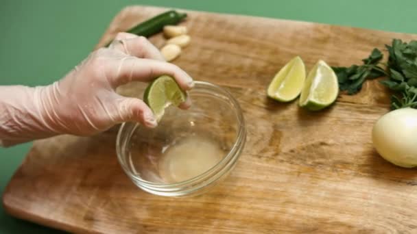 A női kéz friss lime-ot présel. A citromlé beleesik egy üvegtálba. Salsa készítésének folyamata - Felvétel, videó