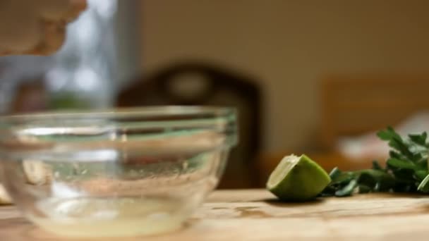Female hands squeeze a fresh lime. Drops of lime juice fall into a glass bowl. Process of making salsa - Footage, Video