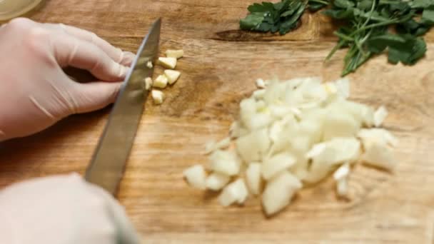 Tagliare l'aglio con un coltello. Le mani degli chef tagliano a pezzetti gli spicchi d'aglio. Processo di preparazione della salsa - Filmati, video